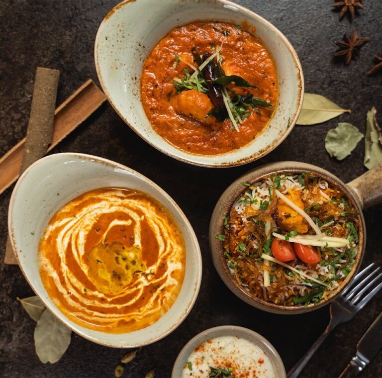 Three bowls of delicious Indian food on a table at an Indian restaurant.